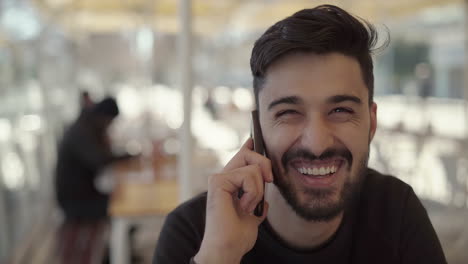 Handsome-young-man-talking-by-smartphone-and-laughing